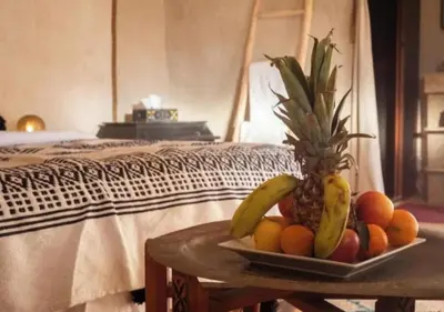 a plate of fruit on a table next to a bed at Solaris Luxury Camp in Merzouga