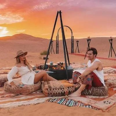 a man and a woman sitting on large tires in the desert at Solaris Luxury Camp in Merzouga