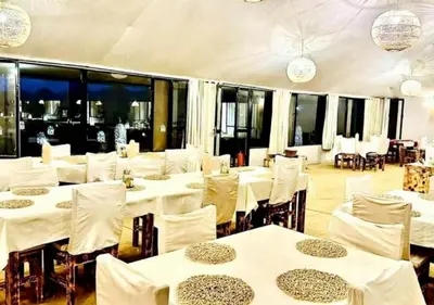 a restaurant with white tables and chairs and windows at Solaris Luxury Camp in Merzouga