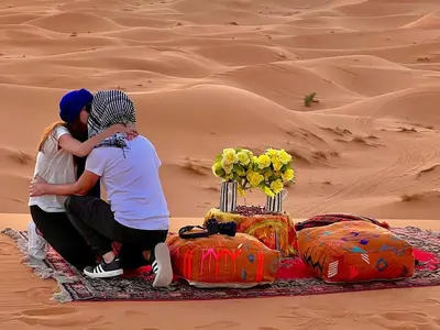 a man and a woman sitting in the desert at Big Dipper Luxury Camp in Merzouga