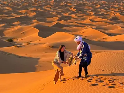 a man and a woman walking through the desert at Big Dipper Luxury Camp in Merzouga