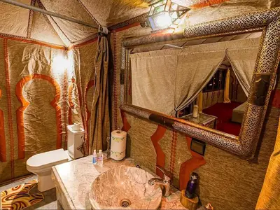 a bathroom with a sink and a toilet and a mirror at Big Dipper Luxury Camp in Merzouga