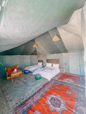 a bedroom in a tent with a bed and a rug at Big Dipper Luxury Camp in Merzouga