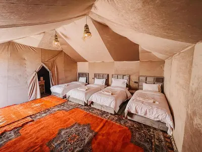 a bedroom with three beds in a tent at Big Dipper Luxury Camp in Merzouga