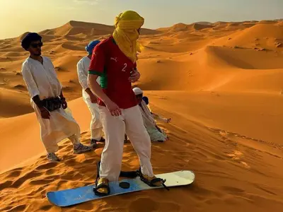 a man standing on a snowboard in the desert at Big Dipper Luxury Camp in Merzouga