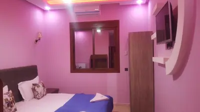 a pink room with a bed and a mirror at Hôtel Ajil Cascades D'ouzoud in Ouzoud