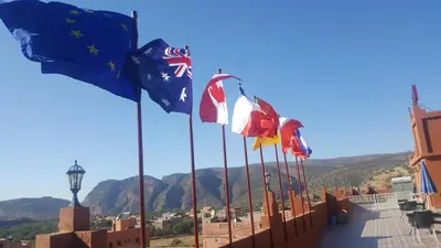 a row of flags on a building with mountains in the background at Hôtel Ajil Cascades D'ouzoud in Ouzoud