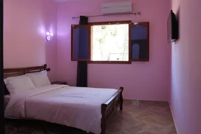 a bedroom with pink walls and a bed with a window at Hôtel Ajil Cascades D'ouzoud in Ouzoud