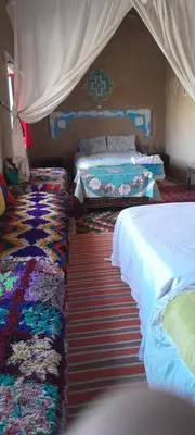 a bedroom with two beds and a rug at Oasis travel in Ksar Tazouga