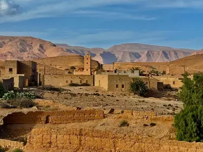 a village in the desert with mountains in the background at Oasis travel in Ksar Tazouga