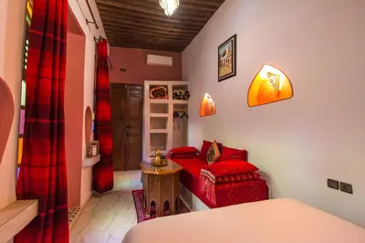 a living room with a red couch and a bed at Riad Dar Mansoura in Fès