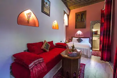 a bedroom with a red couch and a bed at Riad Dar Mansoura in Fès