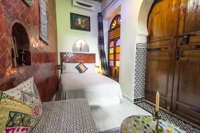 a bedroom with a bed and a wooden door at Riad Dar Mansoura in Fès