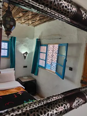 a small room with two beds and a window at Le Retour au calme Maison d'hôtes in Tinerhir