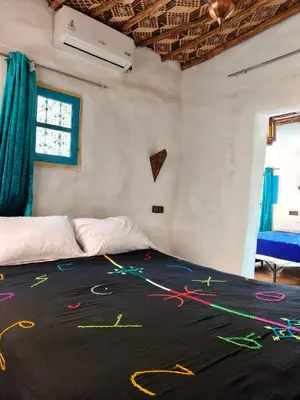 a bedroom with a bed with colorful streamers on it at Le Retour au calme Maison d'hôtes in Tinerhir