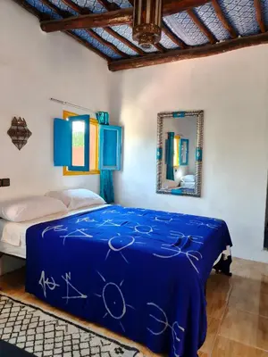a bedroom with a blue bed and a mirror at Le Retour au calme Maison d'hôtes in Tinerhir