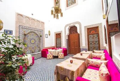 a room with tables and pink furniture in a building at Riad Dar Bab Guissa in Fès