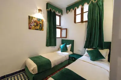 two beds in a room with green curtains at Riad Dar Bab Guissa in Fès