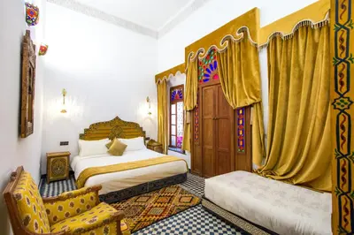 a bedroom with two beds and a chair at Riad Dar Bab Guissa in Fès