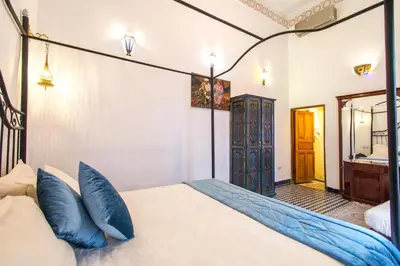 a bedroom with a bed with blue pillows and a mirror at Riad Dar Bab Guissa in Fès