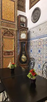 a room with a table and clocks on the wall at Riad Royal in Meknès