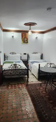 a room with two beds and a table in it at Riad Royal in Meknès