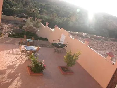 a patio with a table and chairs and a fence at Kasbah Petit Nomade in Tinerhir