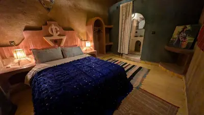 a bedroom with a bed and a cross on the wall at Riad Amar in Merzouga