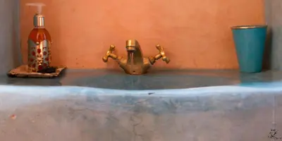 a bathroom sink with a faucet and a blue cup at Riad Amar in Merzouga