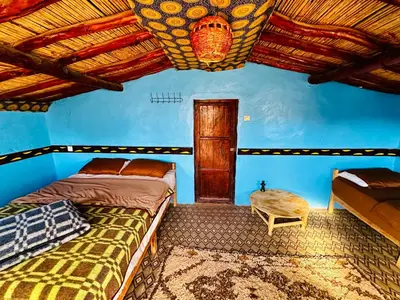 a bedroom with two beds and a blue wall at Desert Tours & Camp Chraika in Mhamid