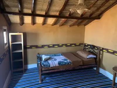 a bedroom with a bed and a wooden ceiling at Desert Tours & Camp Chraika in Mhamid