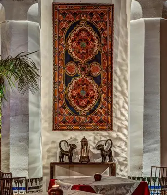 a large rug hanging on a wall with a table at Riad Almaz in Fès