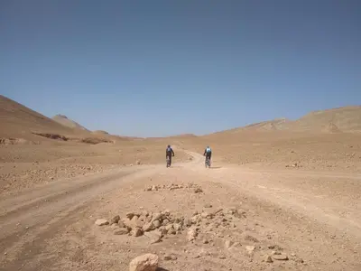 two people walking down a dirt road in the desert at Citadelle Gorges in Ait Ben Ali