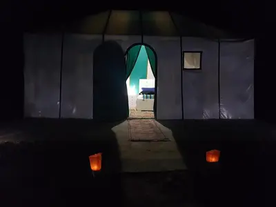 a dark room with a tent with two candles at Dune Merzouga Camp in Merzouga