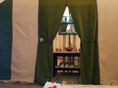 a tent with green curtains in a room at Dune Merzouga Camp in Merzouga