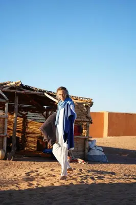 a woman is standing in front of a shack at Sahara Peace in Mhamid