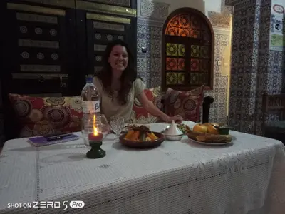 a woman sitting at a table with food on it at Dar Hlimi in Fès