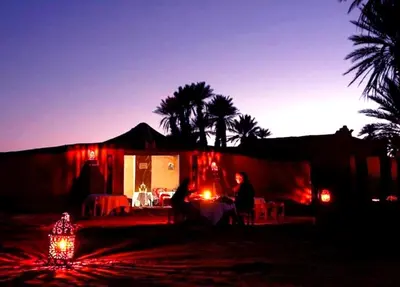 a group of people sitting in front of a house at night at Nomads Life Style in Mhamid