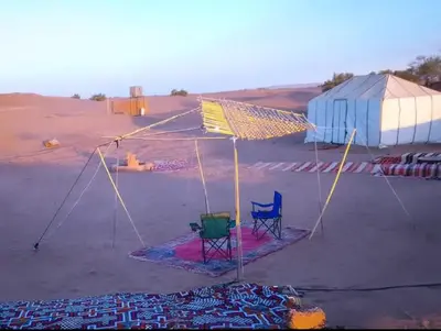 a tent in the middle of a desert with two chairs at Nomads Life Style in Mhamid