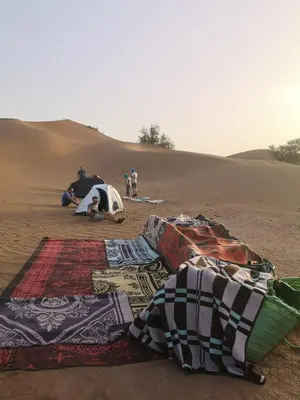 a group of carpets sitting in the desert at Nomads Life Style in Mhamid