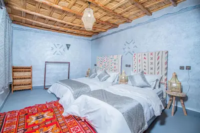 a blue room with two beds and a rug at Dar tiwira in Aït Baha