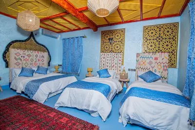 three beds in a room with blue walls at Dar tiwira in Aït Baha