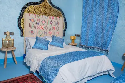 a blue bedroom with a bed with a large headboard at Dar tiwira in Aït Baha