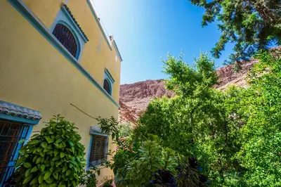 a yellow building with a mountain in the background at Dar tiwira in Aït Baha