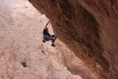 a man is climbing up a rock formation at Dar tiwira in Aït Baha