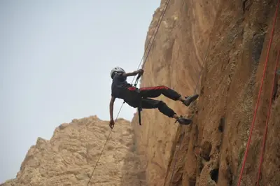 a man on a rock climbing on a cliff at Dar tiwira in Aït Baha
