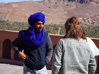 a man wearing a blue hijab standing next to a woman at Sahara Peace camp in Zagora