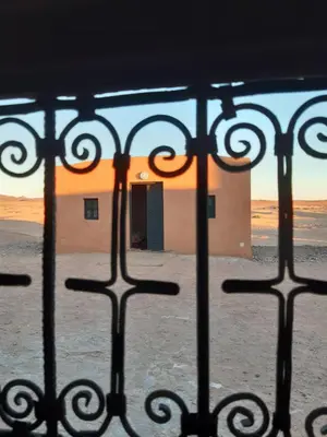 a view of a building through a fence with a door at Sahara Peace camp in Zagora