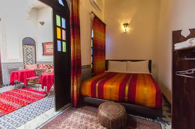 a bedroom with a bed and a room with a table at Riad Taha in Fès