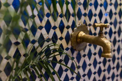 a brass faucet on a wall with a blue at Riad Taha in Fès